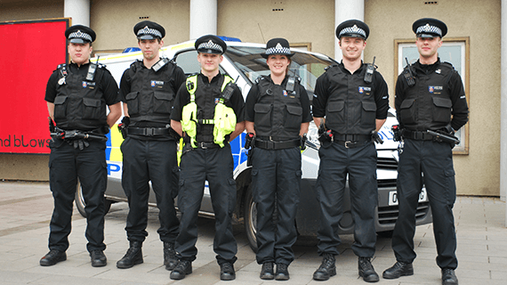 Five BNU policing students in uniform stood in a line in front of a Police van near the Gateway reception on the High Wycombe campus.